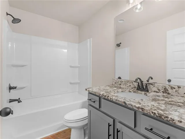 a bathroom with a granite countertop sink a toilet and bathtub