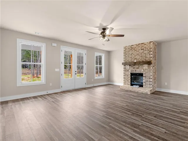 a view of an empty room with window and wooden floor