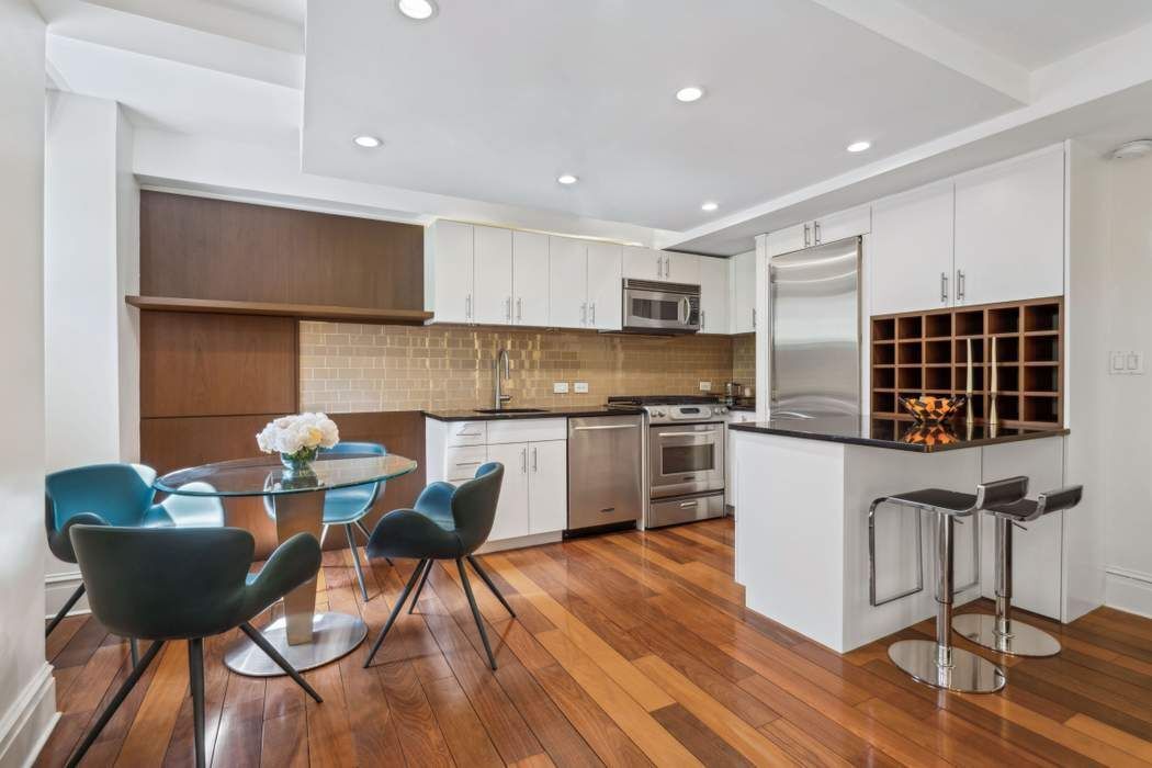 333 East 53rd Street, Unit 1J Manhattan, NY 10022 - Photo 3 of 15 a kitchen with a table chairs a sink and a stove