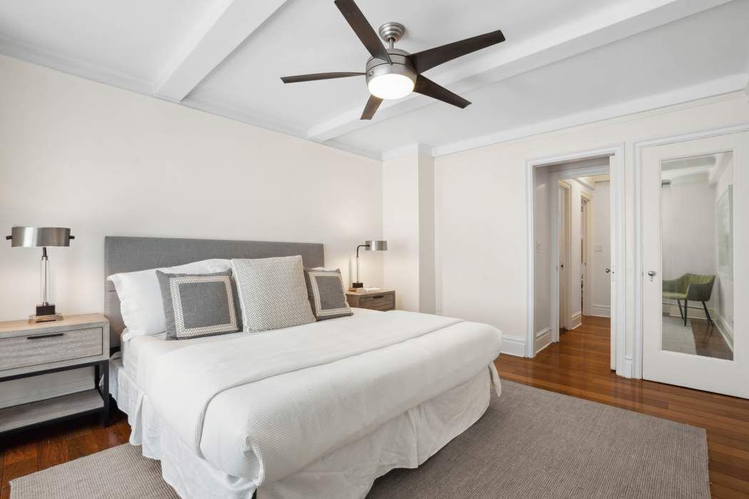 333 East 53rd Street, Unit 1J Manhattan, NY 10022 - Photo 4 of 15 a bedroom with a large bed and a chandelier
