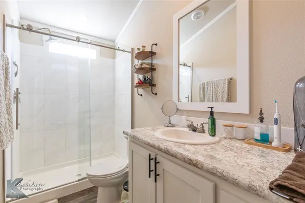 a bathroom with a granite countertop sink toilet and shower