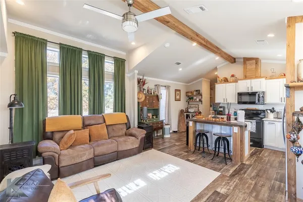 a living room with furniture a large window and stainless steel appliances