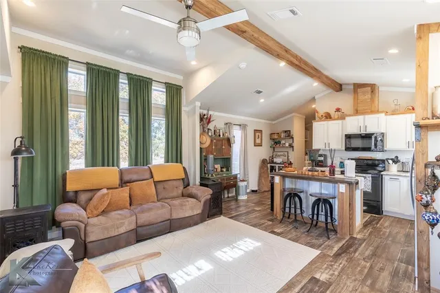 a living room with furniture a large window and stainless steel appliances