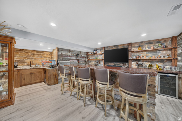 3644 Spiral Springs Road Tooele, UT 84074 - Photo 23 of 41 Lower-level entertaining area featuring a built-in wet bar with stone-clad facade, wood-finish cabinetry, and a wine refrigerator