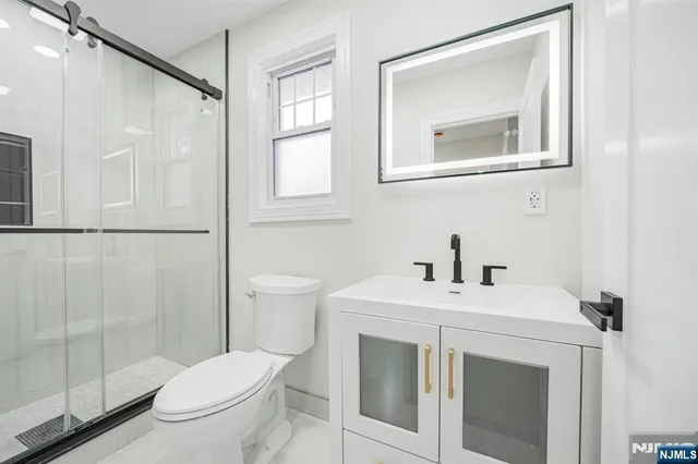 a bathroom with a sink vanity mirror and toilet