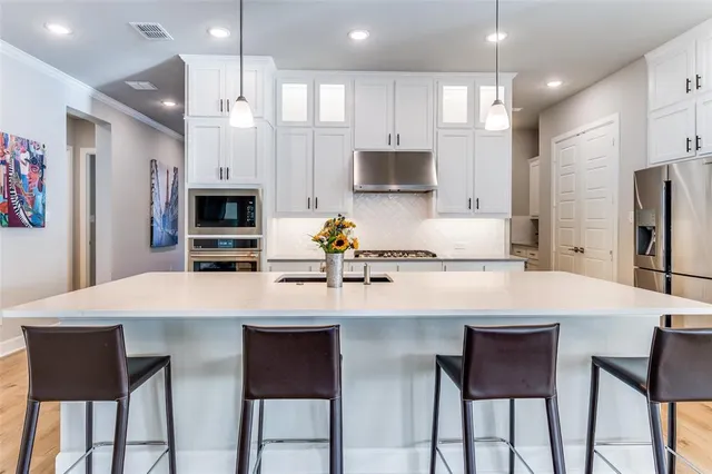 a kitchen with stainless steel appliances a table chairs refrigerator and microwave