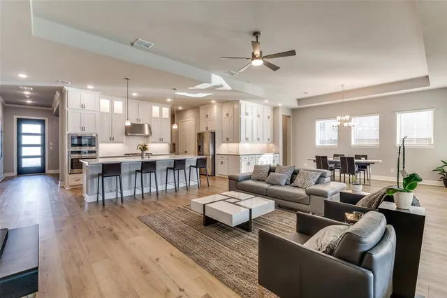 a living room with furniture kitchen view and a wooden floor