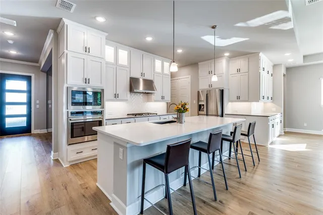 a kitchen with stainless steel appliances kitchen island granite countertop a table chairs sink and cabinets