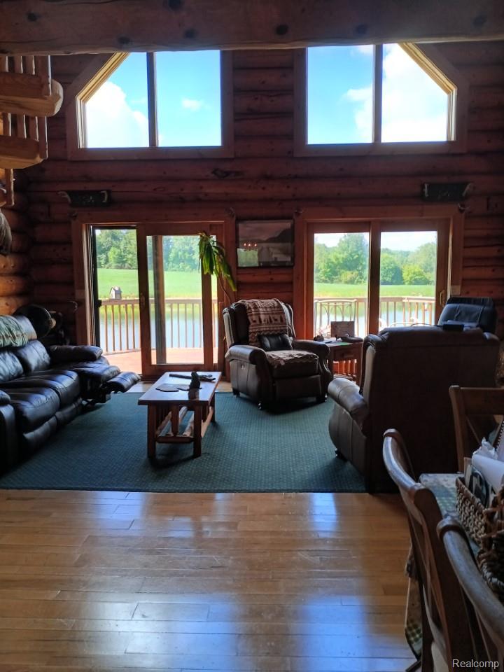 10374 Wilson Road Otisville, MI 48463 - Photo 52 of 99 Living room featuring hardwood / wood-style flooring, log walls, and a towering ceiling