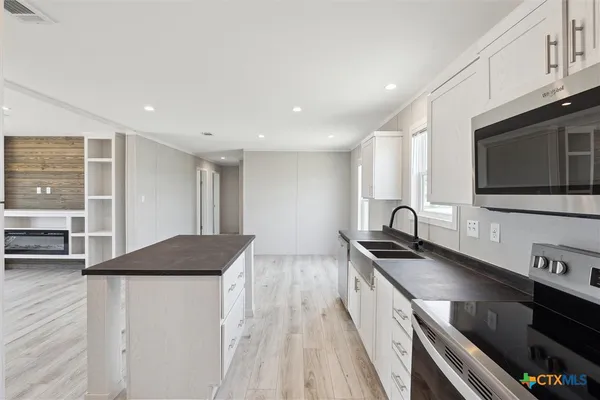 a kitchen with stainless steel appliances kitchen island granite countertop a stove and a sink