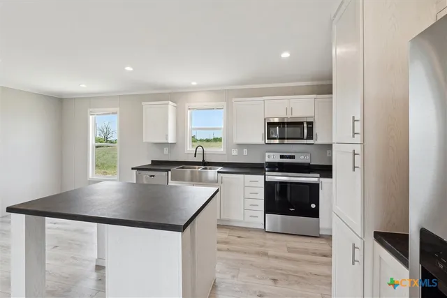 a kitchen with granite countertop a stove a sink and a refrigerator