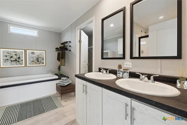 a bathroom with a sink double vanity granite tub and a mirror