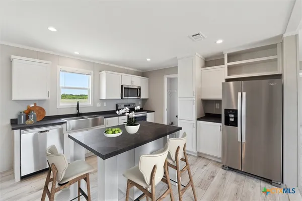 a kitchen with stainless steel appliances granite countertop a refrigerator a stove a sink a dining table and chairs with wooden floor