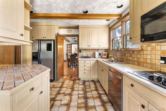a large white kitchen with granite countertop a sink window and cabinets