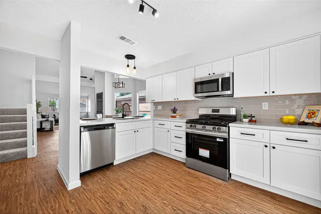 a kitchen with stainless steel appliances granite countertop a sink a stove and cabinets