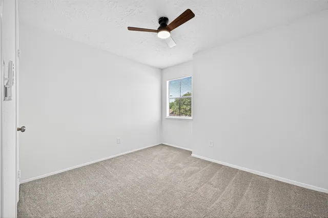 an empty room with ceiling fan and window