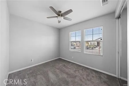 an empty room with ceiling fan and windows