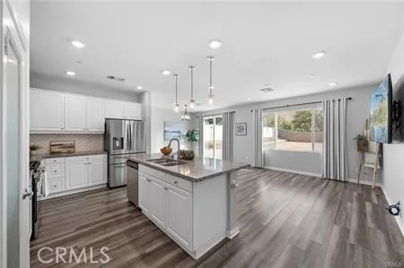 a kitchen with stainless steel appliances kitchen island wooden floors wooden cabinets and a refrigerator