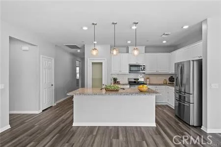 a large kitchen with stainless steel appliances kitchen island granite countertop a refrigerator and a stove top oven