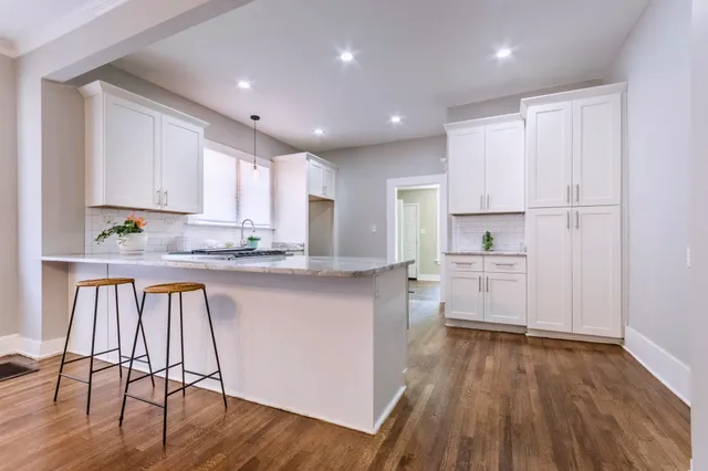 a open kitchen with stainless steel appliances granite countertop a stove top oven a sink dishwasher and white cabinets with wooden floor