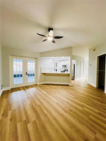 a view of an empty room with a window and a kitchen