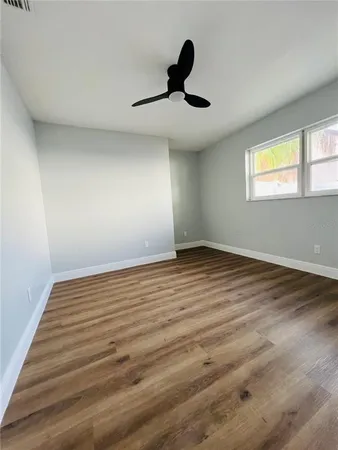a view of empty room with wooden floor and fan