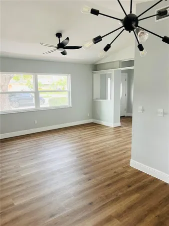 an empty room with wooden floor fan and windows
