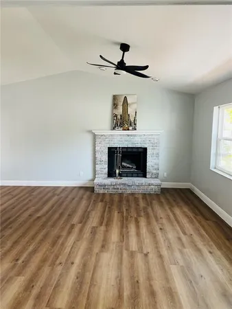 an empty room with wooden floor fireplace and windows