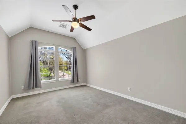 an empty room with windows and ceiling fan