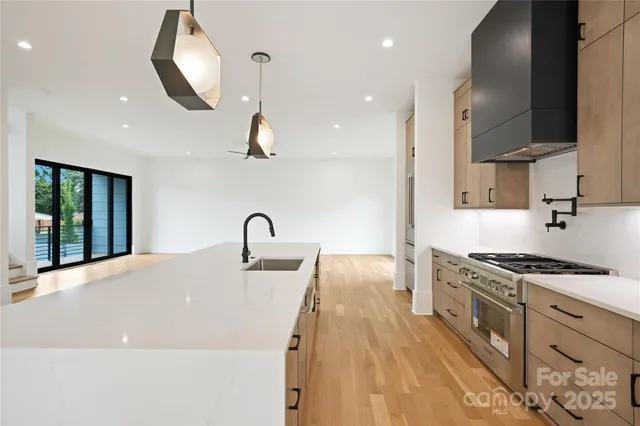 a kitchen with stainless steel appliances granite countertop a sink a stove and a wooden floors