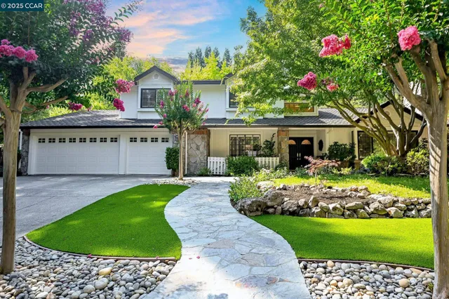 a front view of a house with a garden and trees