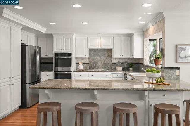 a kitchen with stainless steel appliances granite countertop a table chairs sink refrigerator and microwave