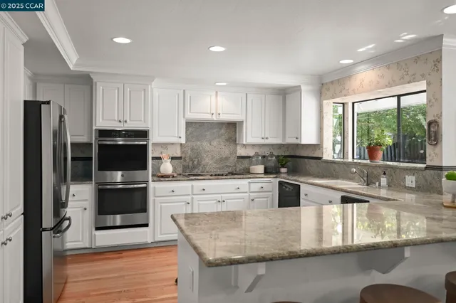 a kitchen with stainless steel appliances granite countertop a stove a sink and a refrigerator