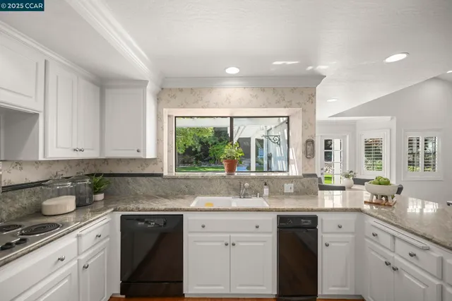 a kitchen with granite countertop a sink and white cabinets
