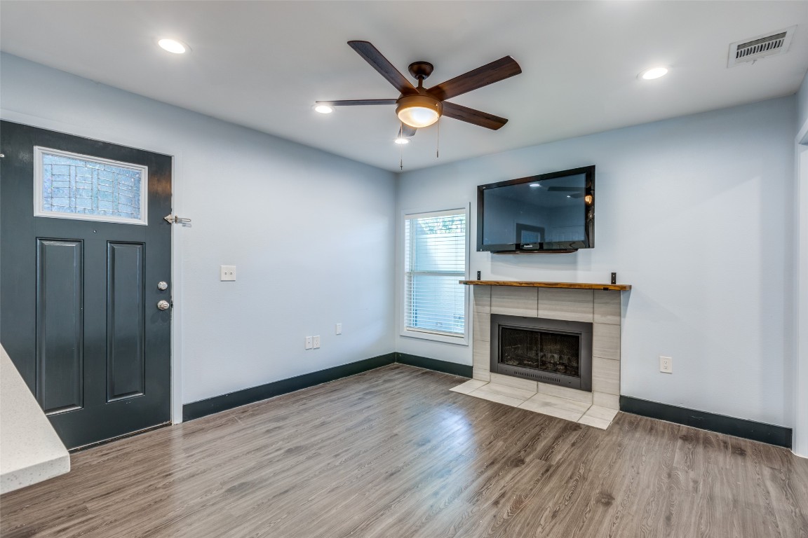 935 La Posada Drive, Unit 155 Austin, TX 78752 - Photo 2 of 25 Unfurnished living room with wood finished floors, a tile fireplace, ceiling fan, and recessed lighting