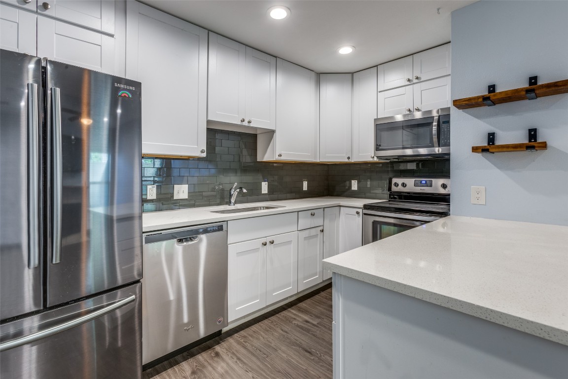 935 La Posada Drive, Unit 155 Austin, TX 78752 - Photo 8 of 25 Kitchen featuring stainless steel appliances, open shelves, light stone countertops, decorative backsplash, and recessed lighting