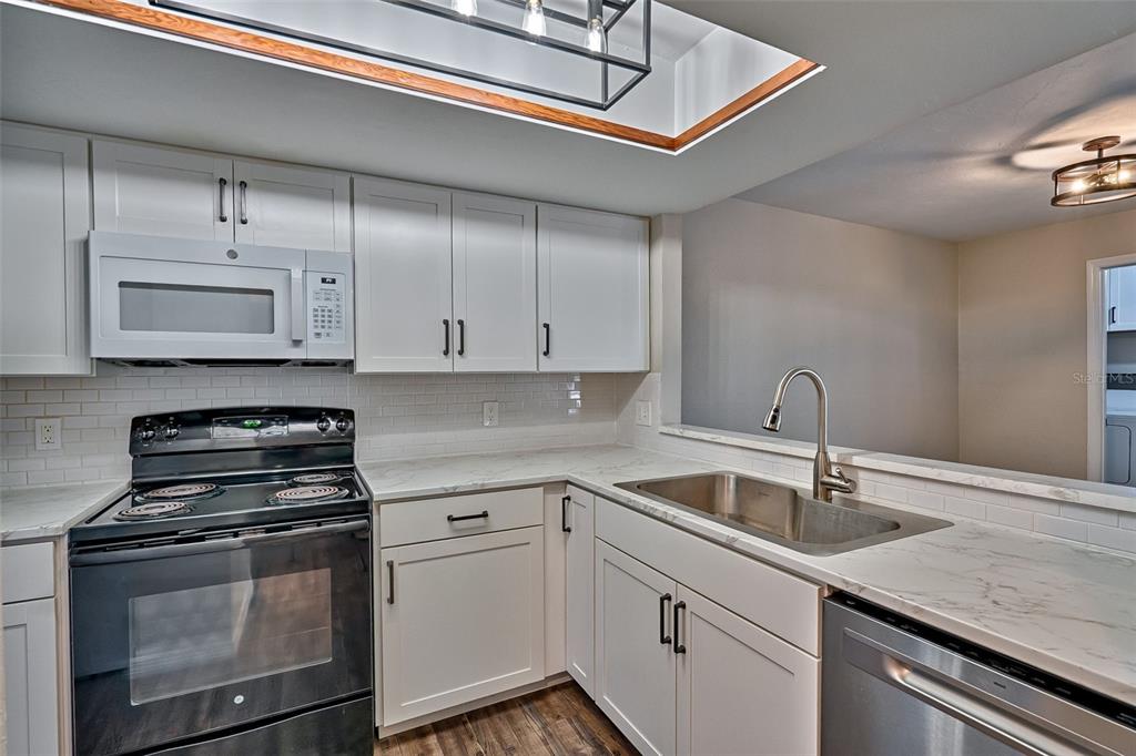 5422 Southwest 4th Place Gainesville, FL 32607 - Photo 11 of 29 a kitchen with granite countertop a sink stainless steel appliances and cabinets