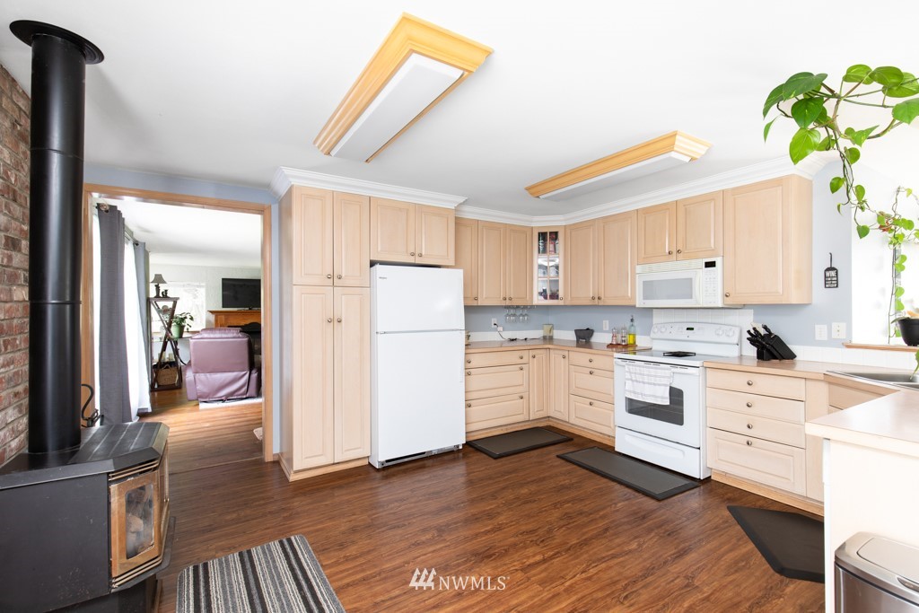 16722 Blodgett Road Mount Vernon, WA 98274 - Photo 25 of 37 a kitchen with a refrigerator a stove and white cabinets with wooden floor