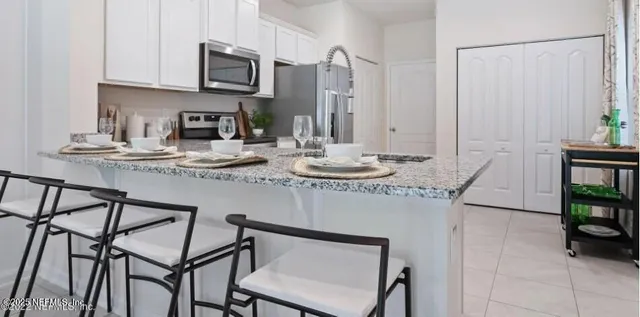a kitchen with stainless steel appliances granite countertop a table chairs sink and cabinets