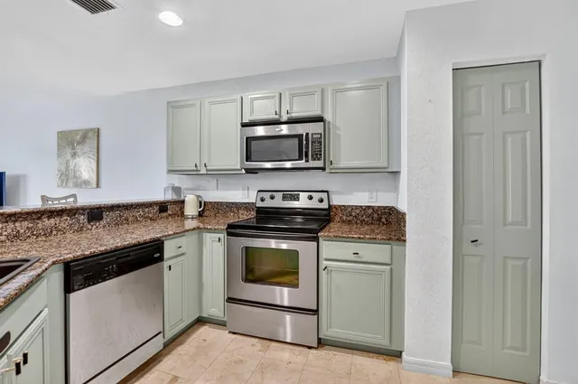 a kitchen with granite countertop a stove top oven and cabinets