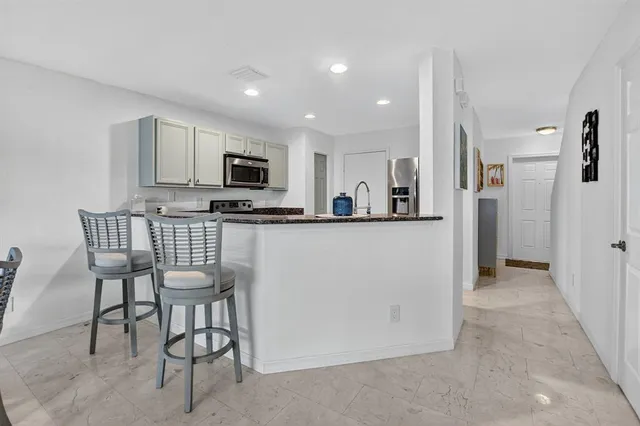 a kitchen with stainless steel appliances kitchen island granite countertop a refrigerator and microwave