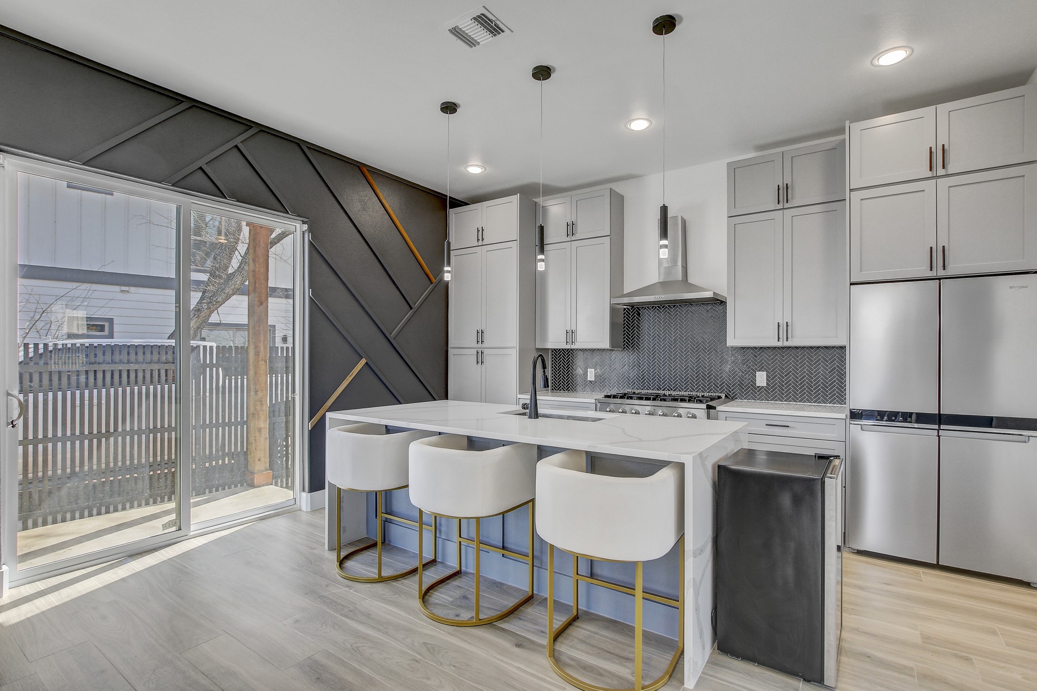 4703 Louis Avenue, Unit A Austin, TX 78721 - Photo 9 of 35 Kitchen with freestanding refrigerator, a breakfast bar, light stone counters, decorative light fixtures, and a kitchen island with sink