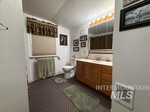 848 Jonathan Road Weiser, ID 83672 - Photo 12 of 42 Full bath with a textured wall, vanity, heating unit, dark colored carpet, and decorative backsplash