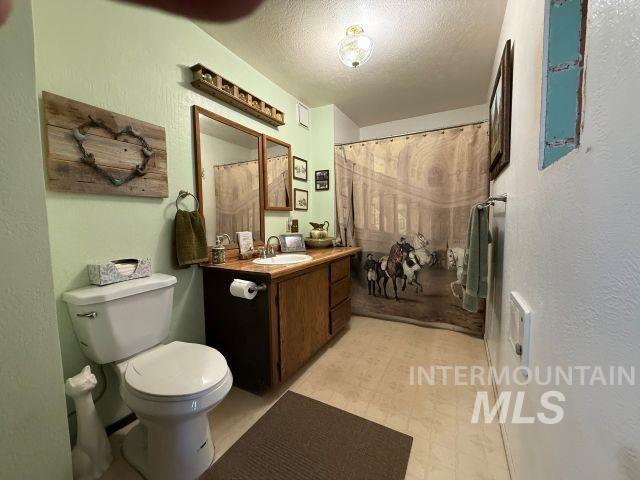 848 Jonathan Road Weiser, ID 83672 - Photo 25 of 42 Full bath with a textured wall, light floors, a textured ceiling, vanity, and curtained shower