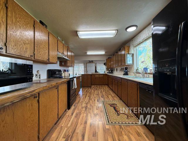 848 Jonathan Road Weiser, ID 83672 - Photo 3 of 42 Kitchen featuring black appliances, wood finish cabinets, light wood-style floors, a textured ceiling, and plenty of natural light