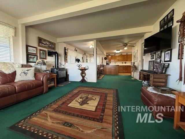 848 Jonathan Road Weiser, ID 83672 - Photo 5 of 42 Carpeted living room with a wood stove, a ceiling fan, and beam ceiling