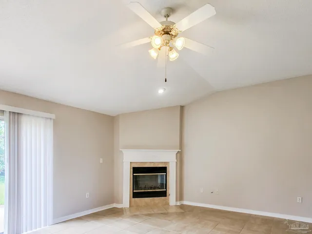 an empty room with a fireplace and a ceiling fan