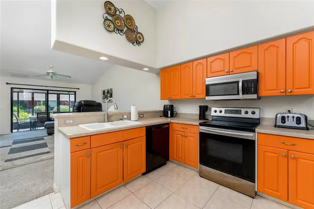 a kitchen with stainless steel appliances a sink a stove a refrigerator with a dining table and chairs