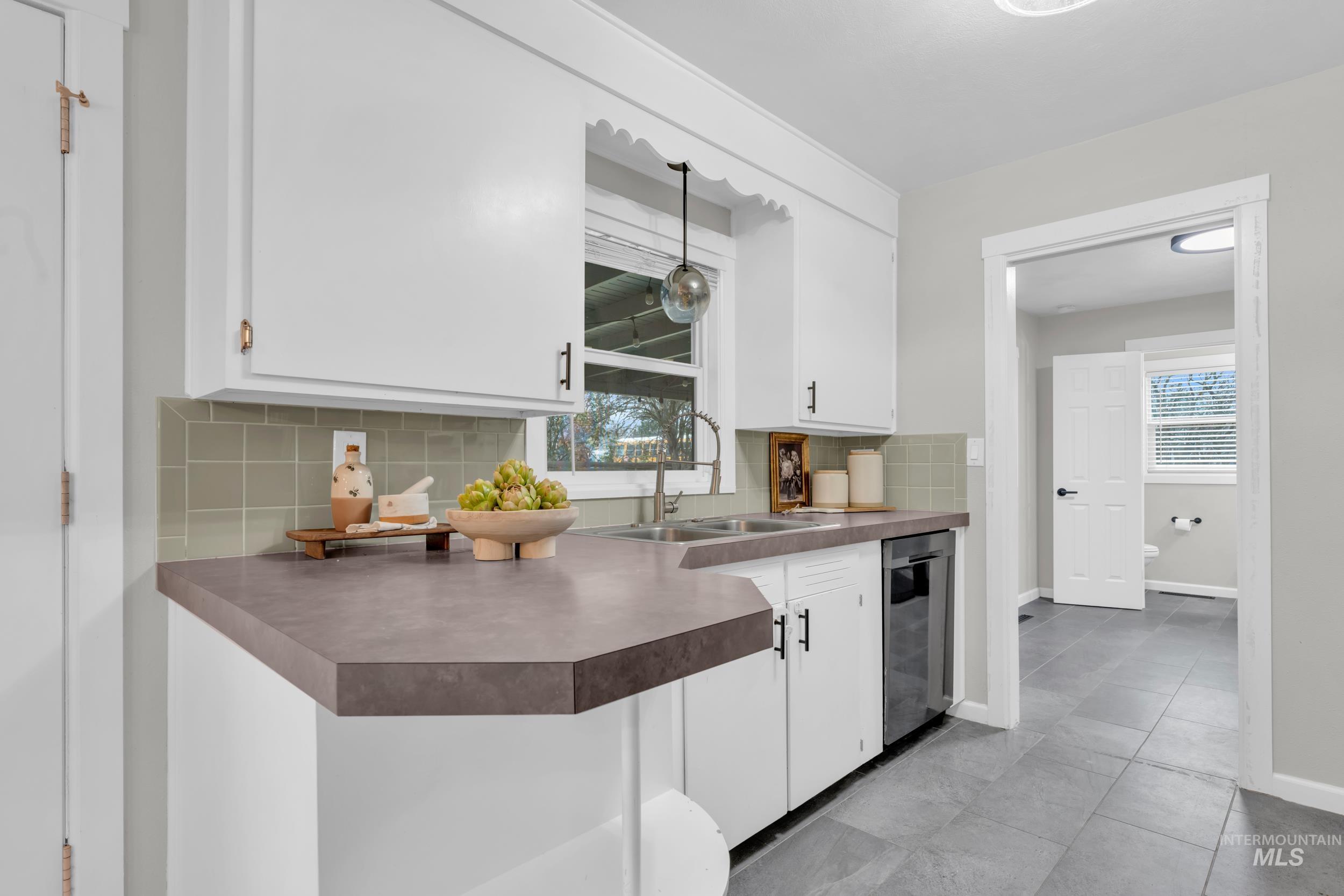 2908 Meadowbrook Drive Boise, ID 83705 - Photo 11 of 29 Kitchen with white cabinets, backsplash, and plenty of natural light