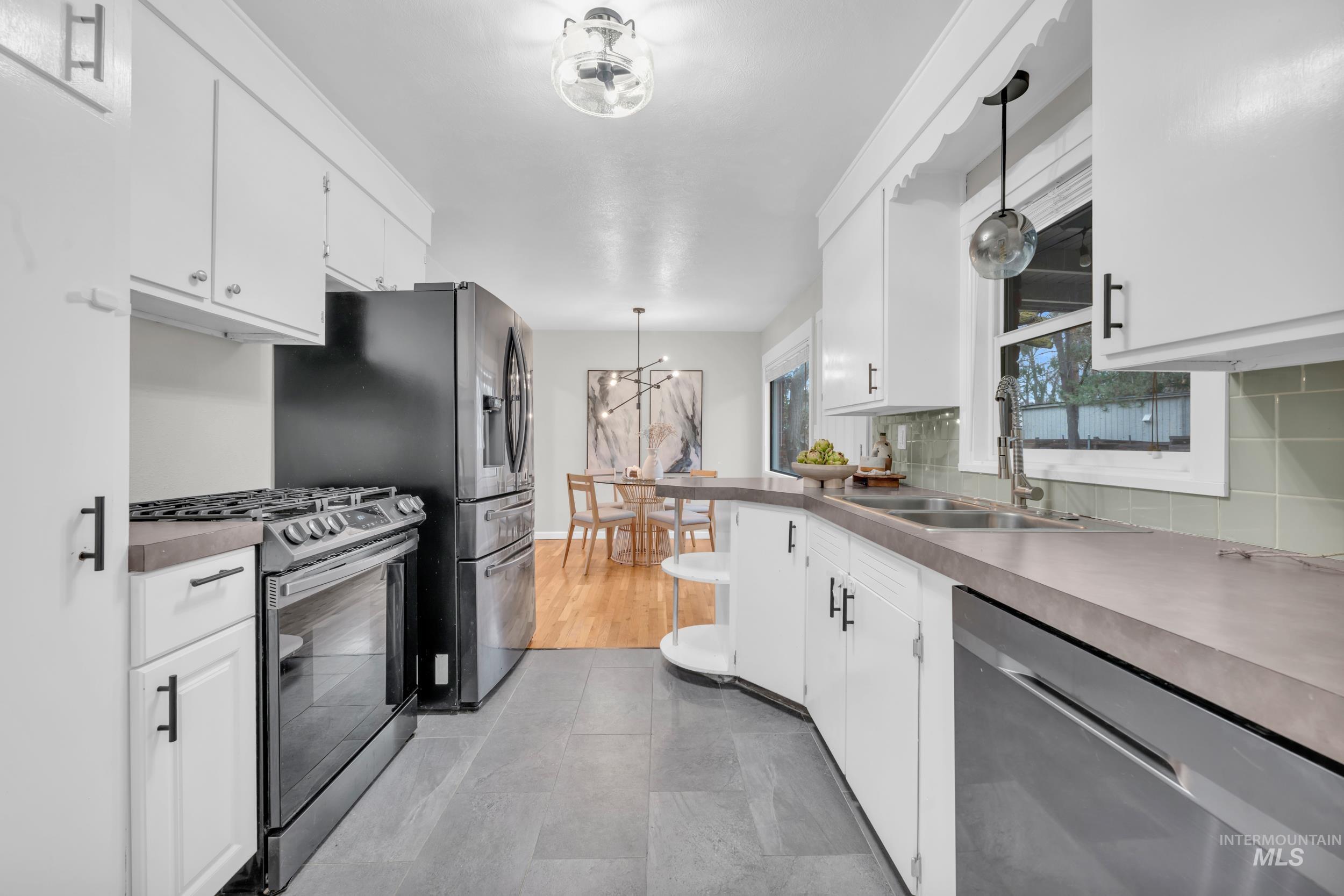 2908 Meadowbrook Drive Boise, ID 83705 - Photo 13 of 29 Kitchen with stainless steel appliances, white cabinets, and pendant lighting